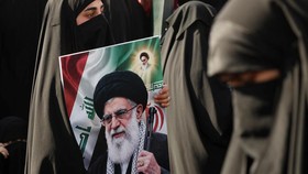 A woman holds a sign featuring a picture of late Supreme Leader Ayatollah Ali Khamenei, who was killed on February 28 in Israeli and U.S. airstrikes, during his funeral procession, in Najaf, Iraq, July 8, 2026. REUTERS/Alaa Al-Marjani