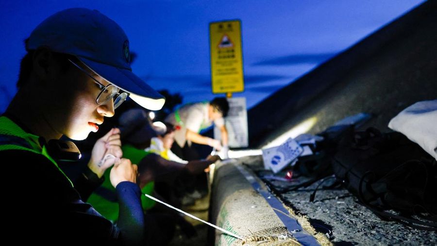 Para sukarelawan memasang karung kopi jejak ke tembok laut sebagai bagian dari proyek untuk membantu kepiting bakau mencapai laut untuk bertelur selama musim kawin tahunan di Taman Nasional Taijiang di Tainan, Taiwan, 3 Juli 2026. (REUTERS/Ann Wang)
