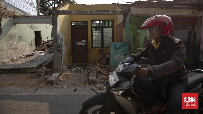 Warga melintas di samping bangunan yang telah dibongkar secara mandiri karena terdampak proyek pembangunan jalan baru di kawasan Pasar Minggu, Jakarta, Rabu (8/7/2026).
