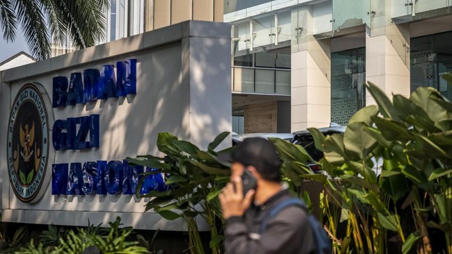 Warga berjalan di dekat Kantor Badan Gizi Nasional (BGN) di Jakarta, Kamis (9/7/2026). Pihak kepolisian membantah adanya peristiwa penembakan di Kantor BGN dan menyatakan pecahnya kaca bangunan diduga disebabkan tingginya suhu luar ruangan yang memic