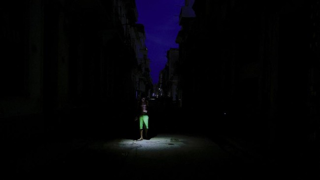 A man uses his phone's flashlight to light his way while walking on a street as Cuba's national electric grid collapsed at midday, leaving around 10 million people without power, in Havana, Cuba, July 6, 2026. REUTERS/Norlys Perez