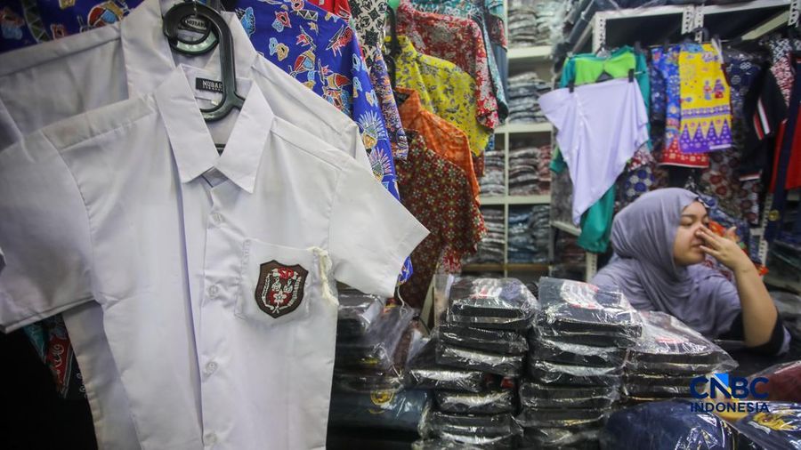 Orang tua mencocokkan seragam sekolah ke anaknya pada toko penyedia seragam sekolah di Pasar Tanah Abang, Jakarta, Kamis (9/7/2026).