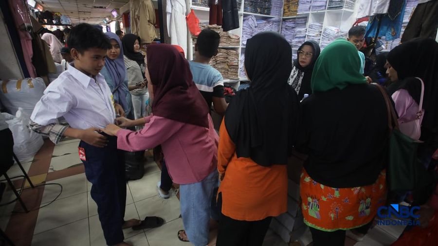 Orang tua mencocokkan seragam sekolah ke anaknya pada toko penyedia seragam sekolah di Pasar Tanah Abang, Jakarta, Kamis (9/7/2026).