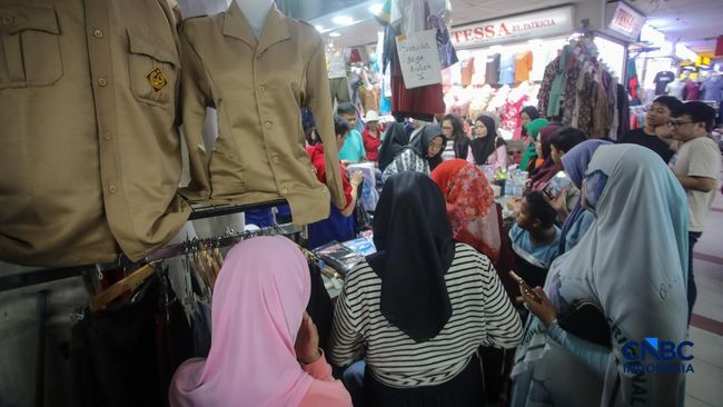 Orang tua mencocokkan seragam sekolah ke anaknya pada toko penyedia seragam sekolah di Pasar Tanah Abang, Jakarta, Kamis (9/7/2026).(CNBC Indonesia/Faisal Rahman)