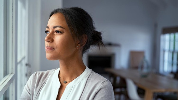 Mature african woman looking outside window with uncertainty&period; Thoughtful mid adult woman looking away through the window while thinking about her future business after pandemic&period; Close up face of doubtful lady at home with pensive expression and copy space&period;
