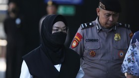 Bupati Sukoharjo Etik Suryani (kiri) dikawal petugas saat tiba untuk menjalani pemeriksaan di Gedung Merah Putih KPK, Jakarta, Jumat (10/7).