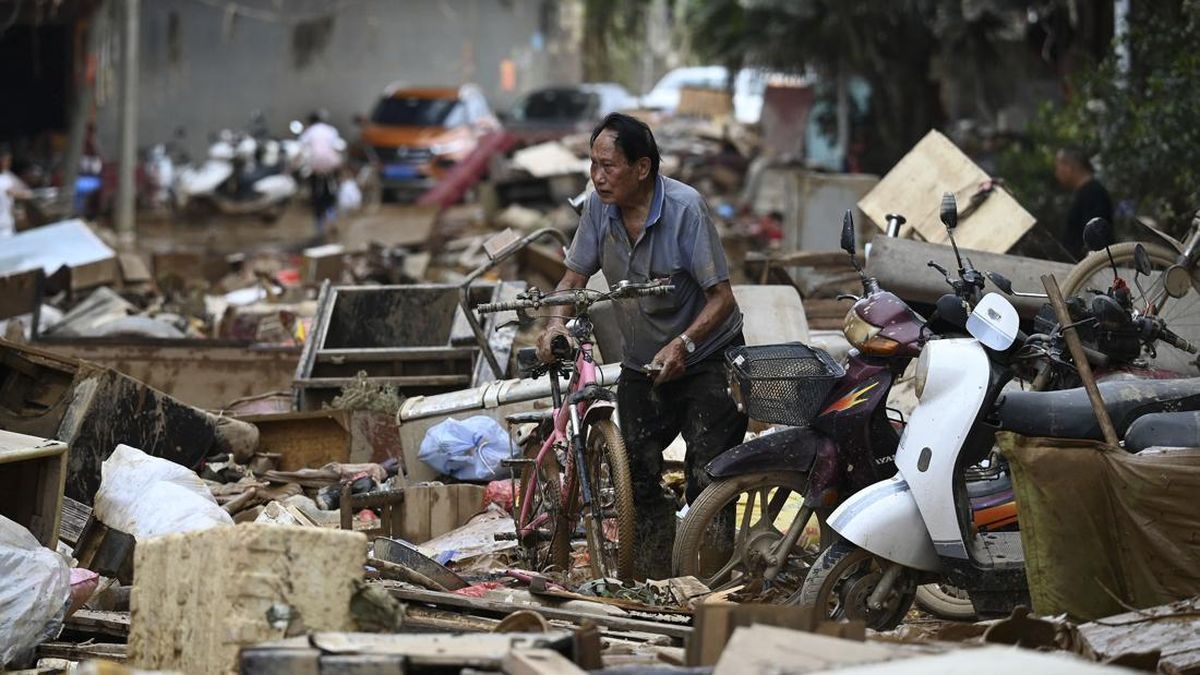 A man collects his bicycle from a pile of belongings outside a row of houses which were flooded up to the second floor when a reservoir collapsed near Gantang, in Chinaís southwest Guangxi region on July 9, 2026. (Photo by GREG BAKER / AFP)