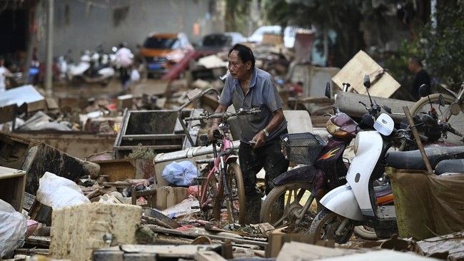 A man collects his bicycle from a pile of belongings outside a row of houses which were flooded up to the second floor when a reservoir collapsed near Gantang, in Chinaís southwest Guangxi region on July 9, 2026. (Photo by GREG BAKER / AFP)