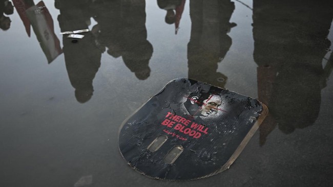 Mourners stand next to a placard calling for revenge as they gather to pay tribute to Iran's slain supreme leader Ayatollah Ali Khamenei at the Grand Mosalla on the second day of funeral ceremonies in Tehran on July 5, 2026. Prayers were held on July
