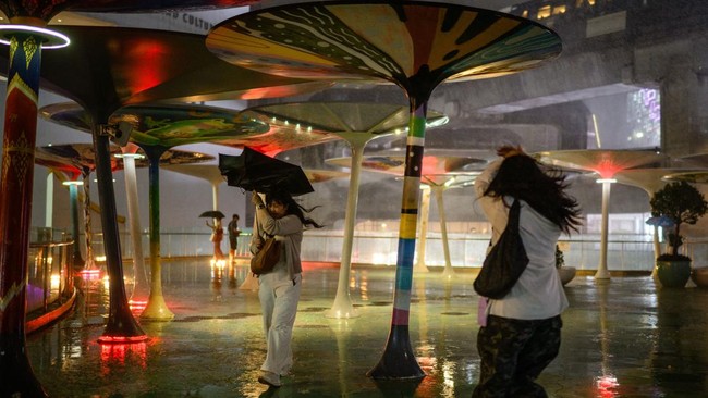 A woman uses an umbrella to shield herself from the rain during a heavy downpour in Bangkok on July 8, 2026. (Photo by Anthony WALLACE / AFP)