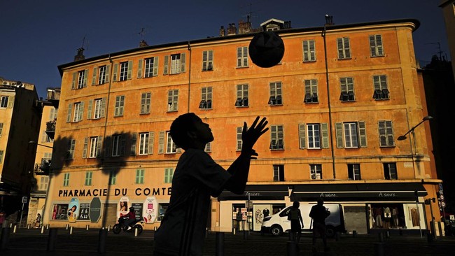 A boy plays with a ball at sunset in Nice on July 8, 2026. (Photo by Valery HACHE / AFP)