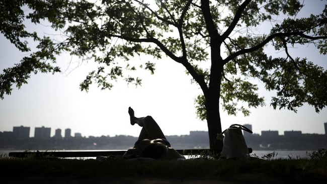 A woman lies in the shade near the banks of the Hudson River in the Manhattan borough during a heatwave in New York City on July 2, 2026. Blistering temperatures and humidity gripped swaths of the United States on July 1, with the worst yet to come f