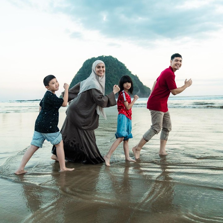 <p>Selain mengunjungi tempat yang dipenuhi pemandangan asri, Nycta Gina dan keluarganya juga menyempatkan diri untuk datang ke Pantai Pulau Mewah yang ada di Kecamatan Pesanggrahan, Banyuwangi. Nycta Gina dan suami ini terlihat begitu bahagia bisa <em>quality time</em> bareng kedua anak mereka yang tengah libur sekolah. (Foto: Instagram @missnyctagina/ @kinosnoski)</p>
