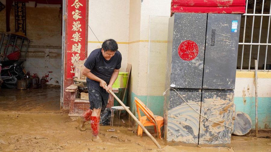 Seorang penduduk membersihkan lumpur dari rumah nan terendam banjir setelah hujan lebat akibat topan Maysak, dekat Waduk Liulan di Hengzhou, Daerah Otonomi Guangxi Zhuang, Tiongkok, 8 Juli 2026.