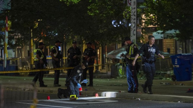 Police officers investigate the site of a shooting that occurred at the Salsa on St. Clair Festival in Toronto on the evening of July 11, 2026. Police in Toronto were searching Saturday night, July 11, for an active shooter who had killed two people