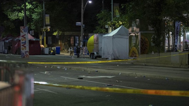 Police officers are seen at the intersection of St. Clair West and Arlington Avenue, near the site of a shooting that occurred at the Salsa on St. Clair Festival in Toronto on the evening of July 11, 2026. Police in Toronto were searching Saturday ni