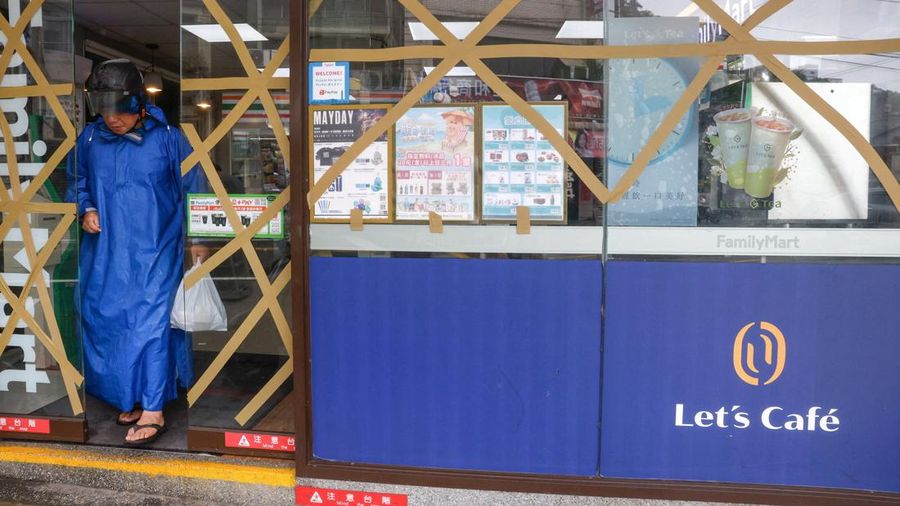 Seorang laki-laki nan mengenakan ponco hujan meninggalkan toko swalayan saat Topan Bavi mendekati pantai utara Taiwan di Keelung, Taiwan, 11 Juli 2026.
