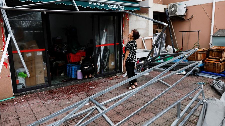 Ye Qiuyan, pemilik sebuah toko, memandang tenda nan rusak akibat Topan Bavi di desa pesisir Diaocaocun, Taizhou, provinsi Zhejiang, Tiongkok, 12 Juli 2026.