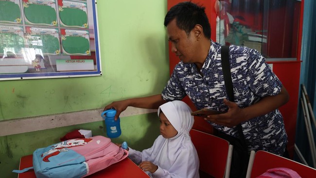Seorang ayah membantu menyiapkan perlengkapan sekolah anaknya di dalam kelas pada hari pertama tahun ajaran 2026/2027 di SDN 5 Pontianak, Kalimantan Barat, Senin (13/7/2026). Kegiatan tersebut merupakan bagian dari program pemerintah yang mendorong k