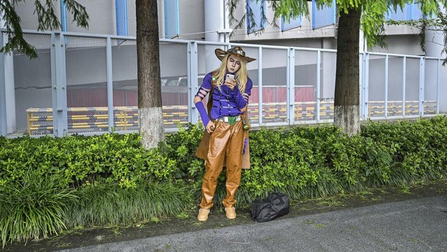 A cosplayer looks at his phone while arriving outside the venue of the Bilibili World 2026 in Shanghai on July 12, 2026. (Photo by Hector RETAMAL / AFP)