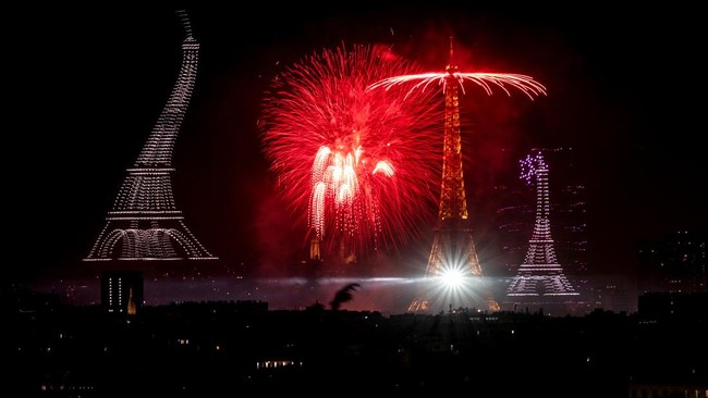 Fireworks and drones light up the sky around the Eiffel Tower during a choreographed show marking Bastille Day in Paris on July 13, 2026, on the eve of the annual Bastille Day parade in the French capital. (Photo by Martin BUREAU / AFP)