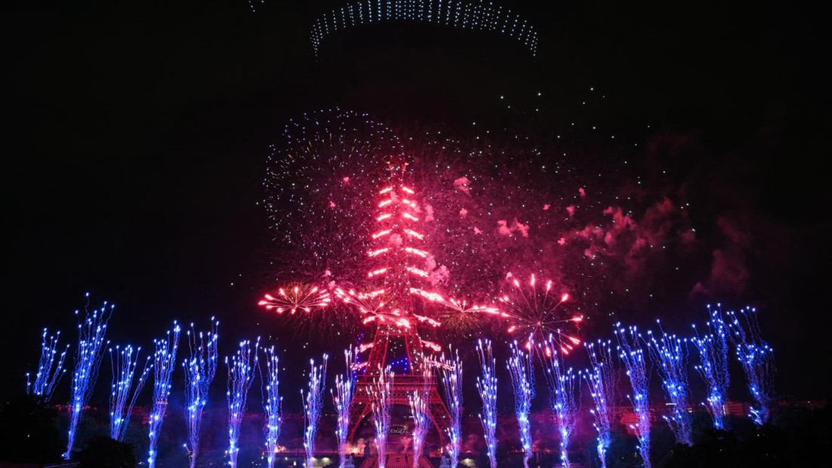 Fireworks and drones light up the sky around the Eiffel Tower during a choreographed show marking Bastille Day in Paris on July 13, 2026, on the eve of the annual Bastille Day parade in the French capital. (Photo by LOU BENOIST / AFP)