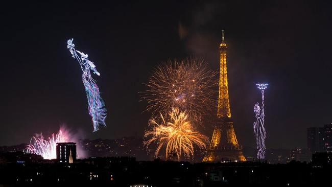 Fireworks and drones light up the sky around the Eiffel Tower during a choreographed show marking Bastille Day in Paris on July 13, 2026, on the eve of the annual Bastille Day parade in the French capital. (Photo by Martin BUREAU / AFP)