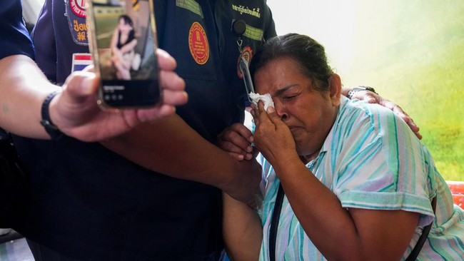 A family member reacts as she receives the body of a victim at the Police Hospital morgue, following a deadly fire at a pub in Bangkok, Thailand, July 13, 2026. REUTERS/Arnun Chonmahatrakool