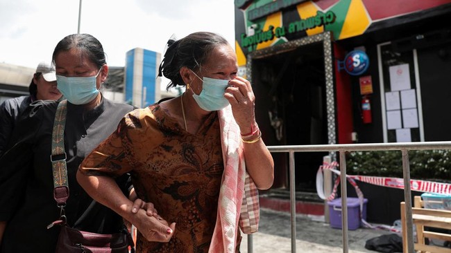 Relatives of the victim, Sitthiphong Chaiyo, 23, from Ubon Ratchathani, visit Rong Beer Na Lat Phrao bar, the site of a deadly fire, to pay tribute to Chaiyo and other victims who lost their lives in the bar fire, the day after the incident, in Bangk