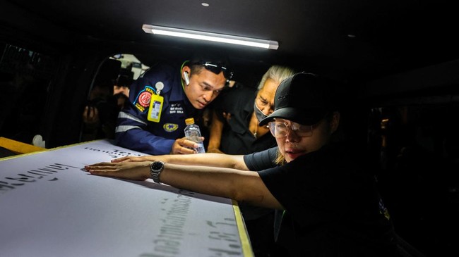 A family member reacts as she receives the body of a victim at the Police Hospital morgue, following a deadly fire at a pub in Bangkok, Thailand, July 14, 2026. REUTERS/Athit Perawongmetha