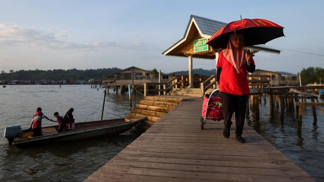 A woman pulls a trolley as she walks on a platform in a water village in Bandar Seri Begawan, Brunei July 16, 2026. REUTERS/Hasnoor Hussain
