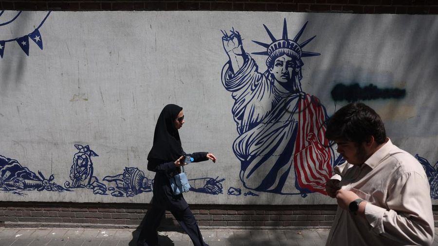 Orang-orang melangkah di dekat mural anti-AS di Teheran, Iran, 15 Juli 2026. (via REUTERS/Majid Asgaripour)