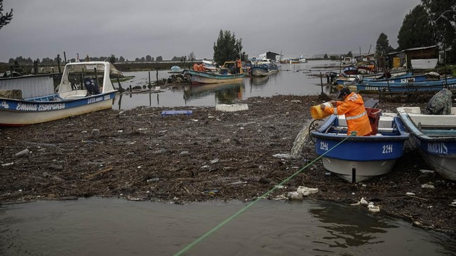 A fisherman removes water from his boat, after the rain during a weather front caused flooding and led the Chilean authorities to declare a preventive state of emergency at the start of the week, in Arauco, Chile, July 16, 2026. REUTERS/Juan Gonzalez