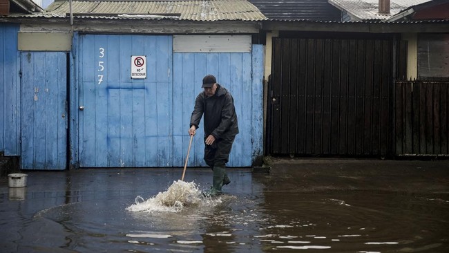A local resident cleans the outside of his house of floodwater from the rain, which occurred during a weather front that led the Chilean authorities to declare a preventive state of emergency at the start of the week, in Arauco, Chile, July 16, 2026.