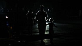 People walk along a street during a nationwide blackout in Havana on July 10, 2026. Cuba suffered its second nationwide blackout in five days on July 10 as twin energy and economic crises, compounded by a six-month US fuel blockade, caused the electr
