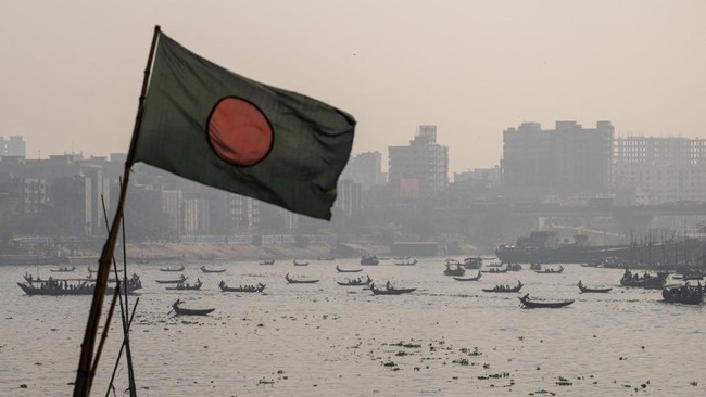 The Bangladeshi national flag flutters as people travel on boats in the Buriganga River in Kamrangirchar on the outskirts of Dhaka on February 14, 2026. (Photo by Mohd RASFAN / AFP)