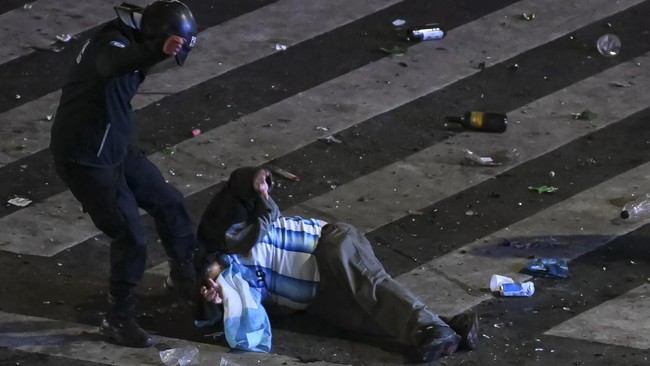 A riot police officer strikes an Argentina fan during clashes at the Obelisk after Argentina lost the FIFA World Cup final football match against Spain in Buenos Aires on July 19, 2026. Spain won by 1-0. (Photo by Luis ROBAYO / AFP)