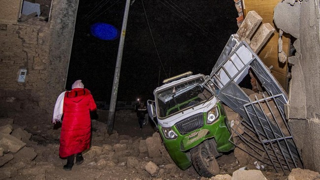 A woman passes by debris following the earthquake of magnitude 5.6 that struck Central Peru on Saturday, in Chupuro, Peru, July 19, 2026. REUTERS/Yershon Vilca