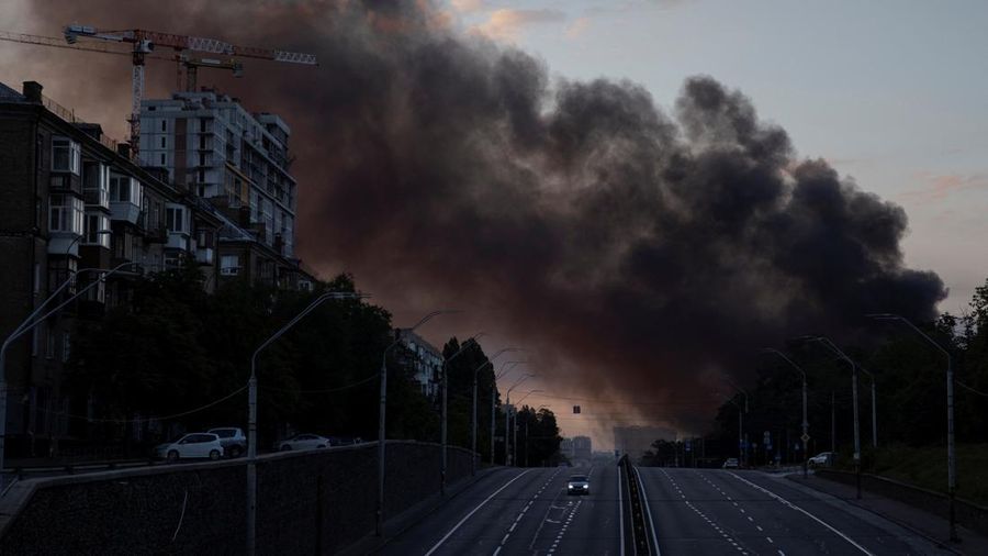 Kepulan asap membubung di atas kota saat sebuah mobil melaju di jalan raya setelah serangan rudal Rusia, di tengah serangan Rusia terhadap Ukraina, di Kyiv, Ukraina, 19 Juli 2026.