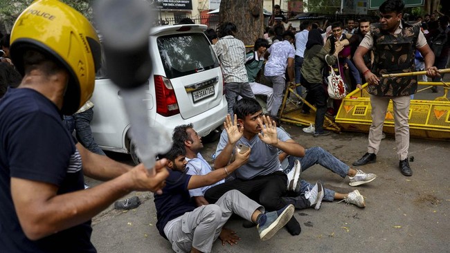 Security force personnel wield batons against demonstrators at a protest site during a planned march by supporters of India's Cockroach Janta Party towards parliament on the opening day of its monsoon session, demanding the resignation of Education M
