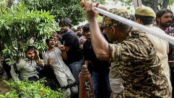 A security force personnel wields his baton against demonstrators at a protest site during a planned march by supporters of India's Cockroach Janta Party towards parliament on the opening day of its monsoon session, demanding the resignation of Educa