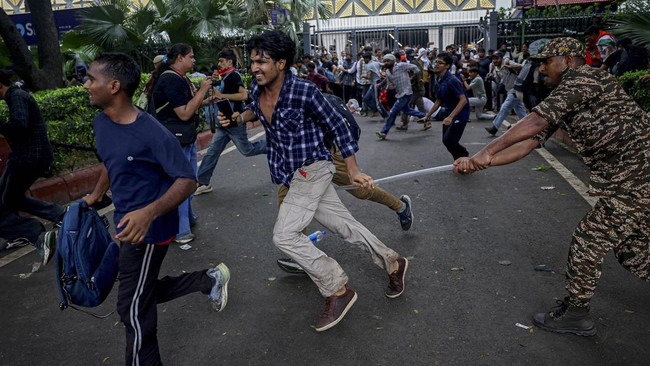 A security force personnel wields his baton against demonstrators at a protest site during a planned march by supporters of India's Cockroach Janta Party towards parliament on the opening day of its monsoon session, demanding the resignation of Educa
