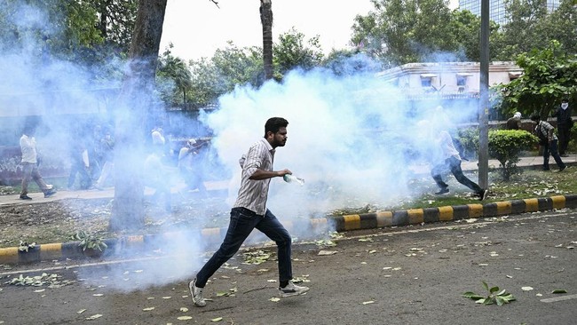 A supporter of the Cockroach Janta Party (CJP) runs as police fire tear gas shells to disperse them during a protest demanding the resignation of India's Education Minister Dharmendra Pradhan over alleged NEET examination irregularities in New Delhi