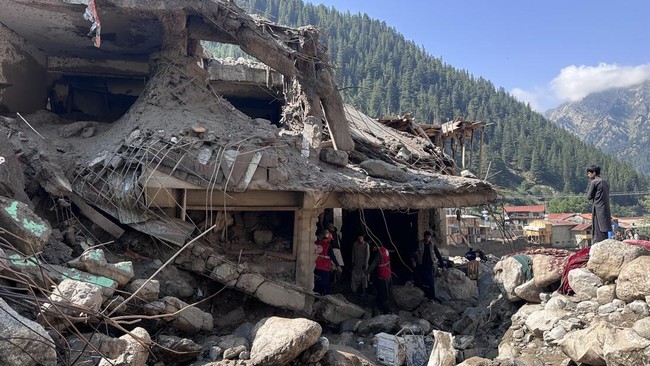 Afghan men search the debris of destroyed shops after flash floods hit Parun town in Afghanistan's Nuristan province, on July 21, 2026. At least 20 people have been killed and more than 100 remain missing in flooding that hit Afghanistan's Nuristan p