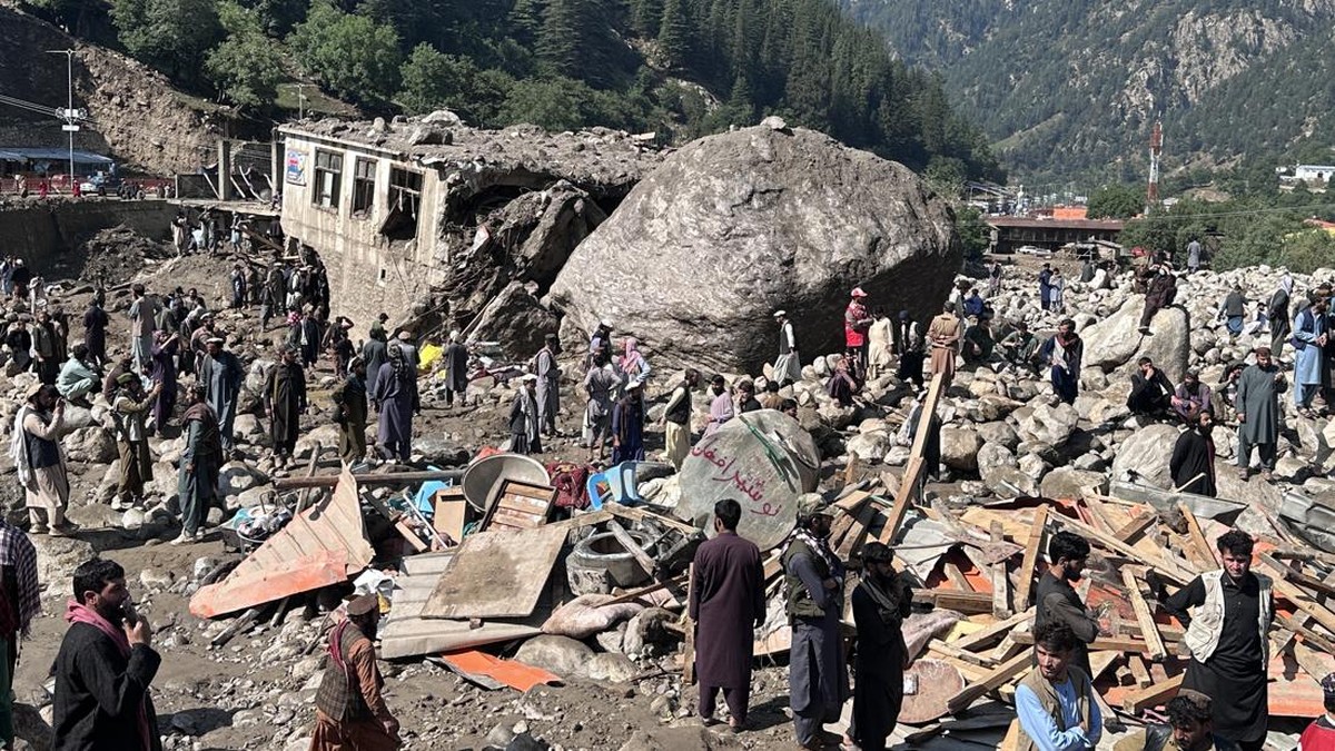 Afghan men stand amidst destroyed shops after flash floods hit Parun town in Afghanistan's Nuristan province on July 21, 2026. At least 20 people have been killed and more than 100 remain missing in flooding that hit Afghanistan's Nuristan province o