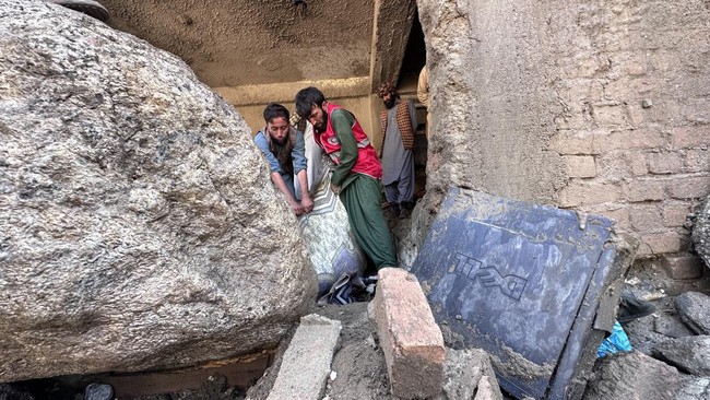 Afghan men search the debris of destroyed shops after flash floods hit Parun town in Afghanistan's Nuristan province, on July 21, 2026. At least 20 people have been killed and more than 100 remain missing in flooding that hit Afghanistan's Nuristan p