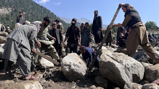 Afghan men search the debris of destroyed shops following flash floods in Parun town in Afghanistan's Nuristan province, on July 21, 2026. At least 20 people have been killed and more than 100 remain missing in flooding that hit Afghanistan's Nurista