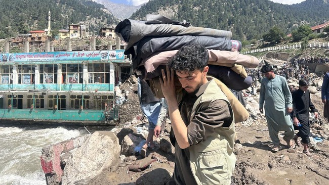 An Afghan man carries his belongings following flash floods in Parun town in Afghanistan's Nuristan province, on July 21, 2026. At least 20 people have been killed and more than 100 remain missing in flooding that hit Afghanistan's Nuristan province
