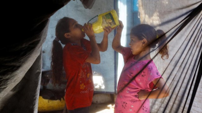 A displaced Palestinian girl drinks water at a tent camp sheltering displaced people, in Nuseirat, central Gaza Strip, July 15, 2026. REUTERS/Mahmoud Issa