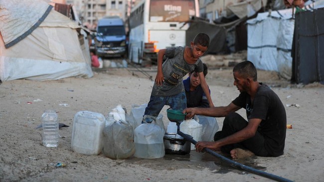 Displaced Palestinians fill water jerrycans at a tent camp sheltering displaced people, in Gaza City, July 14, 2026. REUTERS/Dawoud Abu Alkas
